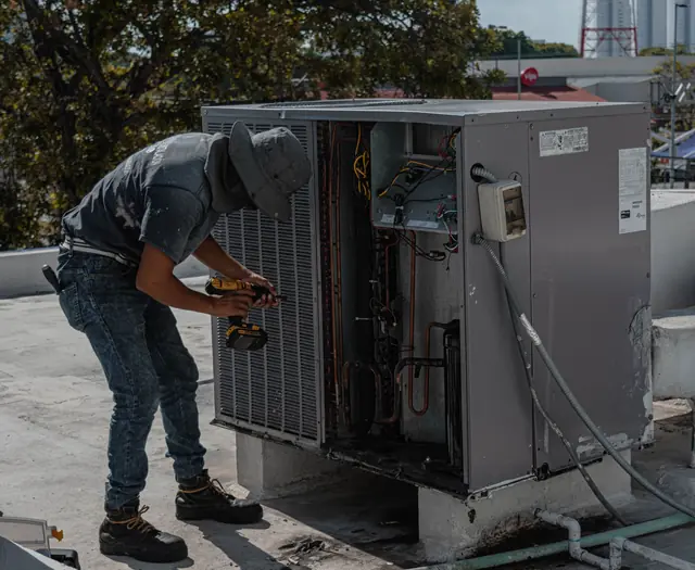 A technician working on a rooftop air conditioner